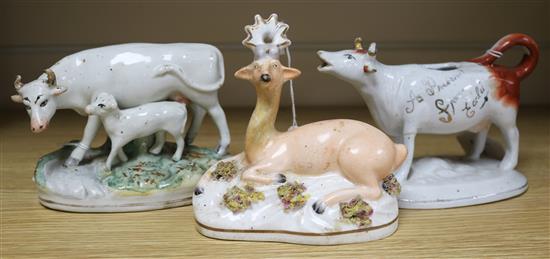 Three Staffordshire figures, a Walton-type recumbent Roe buck, a cow creamer and a cow and calf group (damage and repairs)